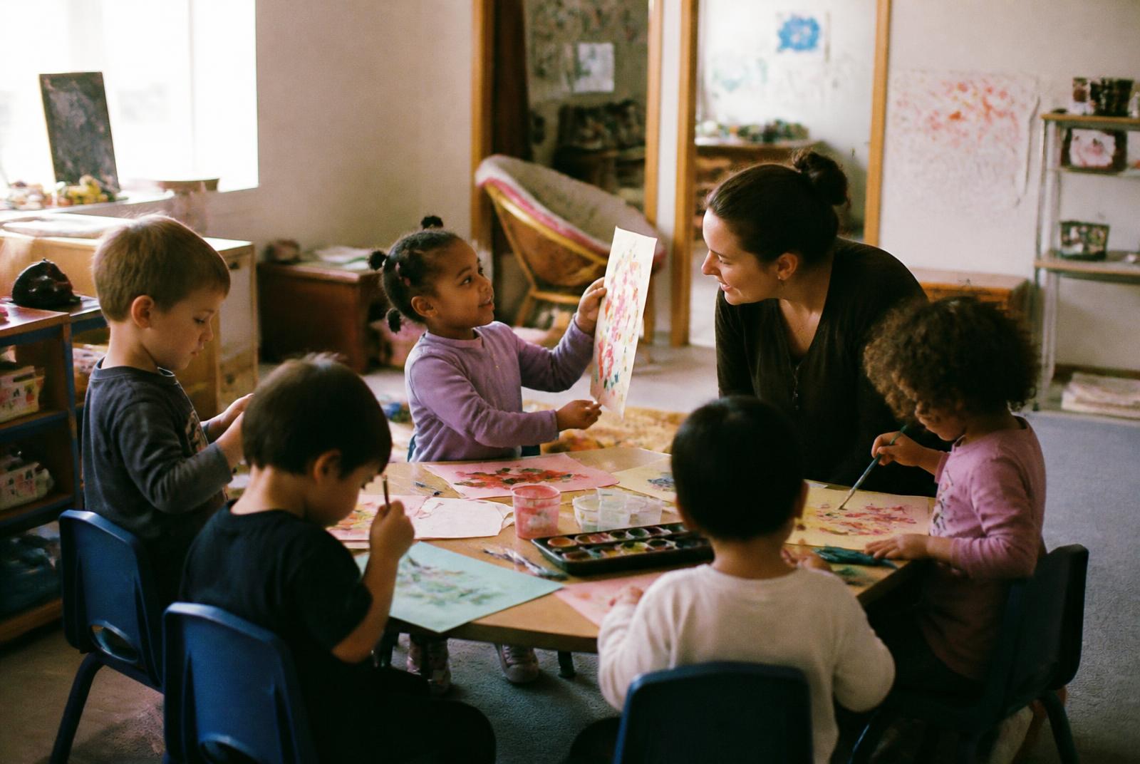 Children painting together with their family home daycare provider